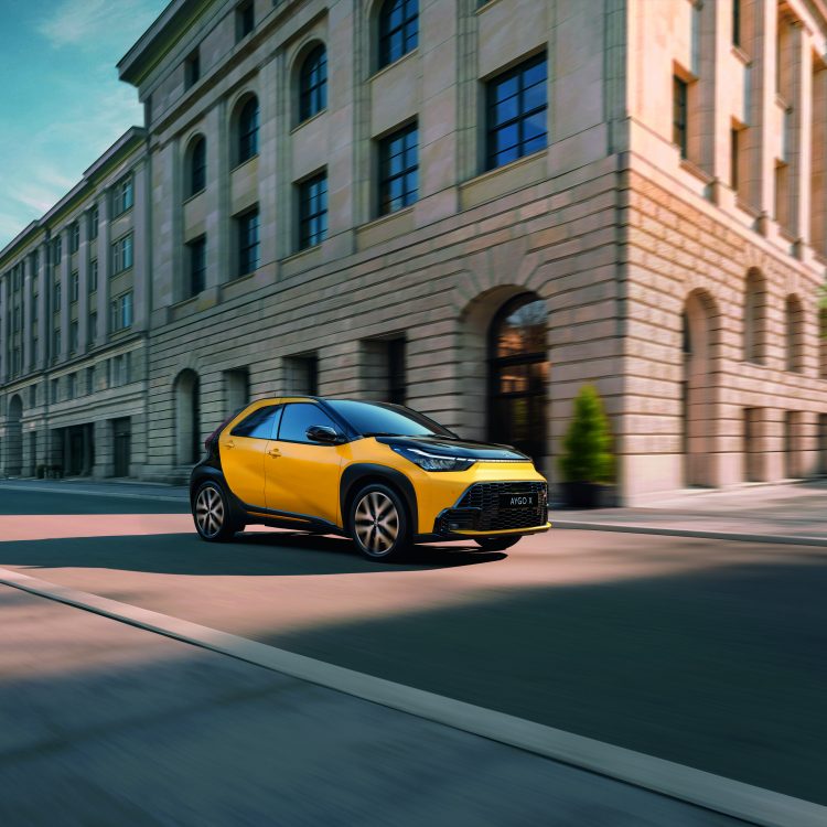 fahrender gelber Aygo in einer Stadt